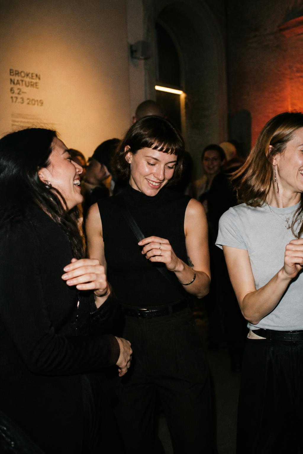 Friends laughing and dancing together in a Stockholm gallery